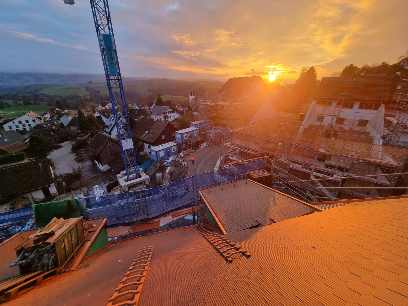 Dacheindeckung bei Sonnenuntergang mit Baukran